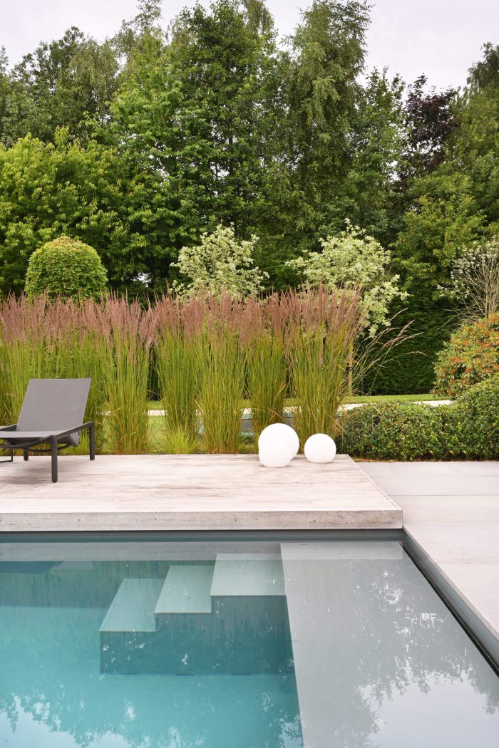 Onderloop zwembad in mooie tuin met ligbedden